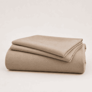 A neatly folded stack of natural linen bed sheets in a warm taupe